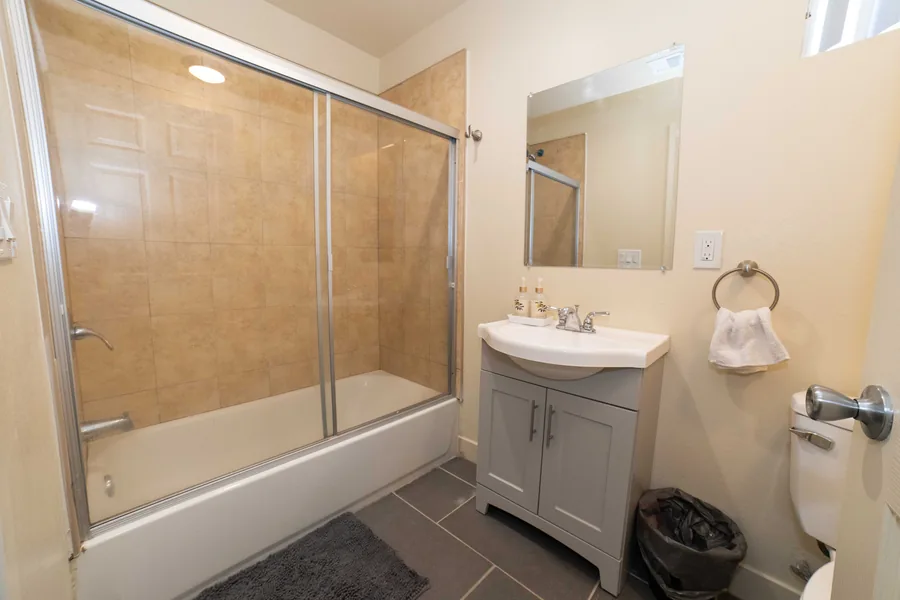 Shared bathroom on East 54th Street with a tub shower a vanity and a wall mirror