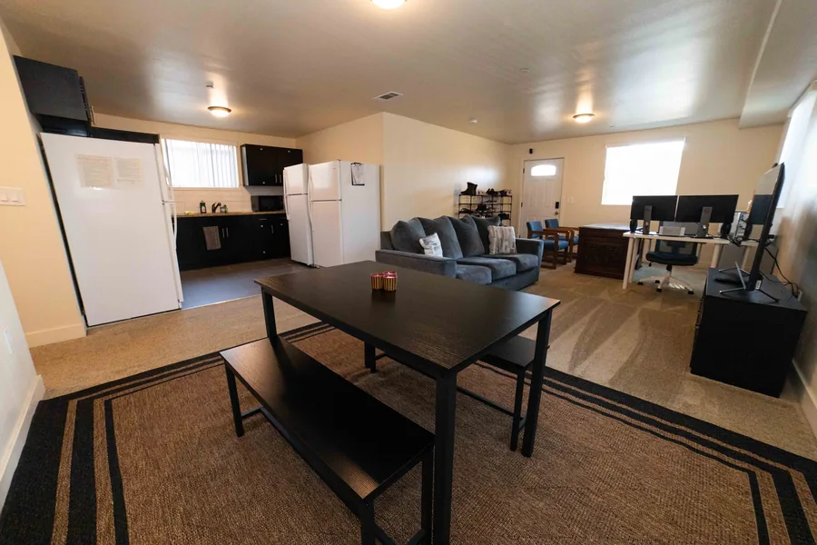 Open plan common room and kitchen at the East 54th Street house with a dining table and two refrigerators