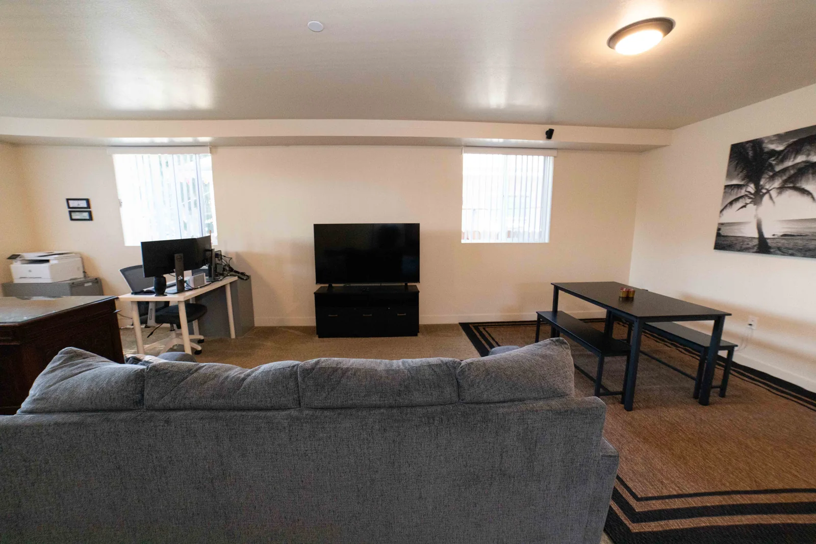 Common room at the East 54th Street house with a sectional sofa a television and a shared work desk