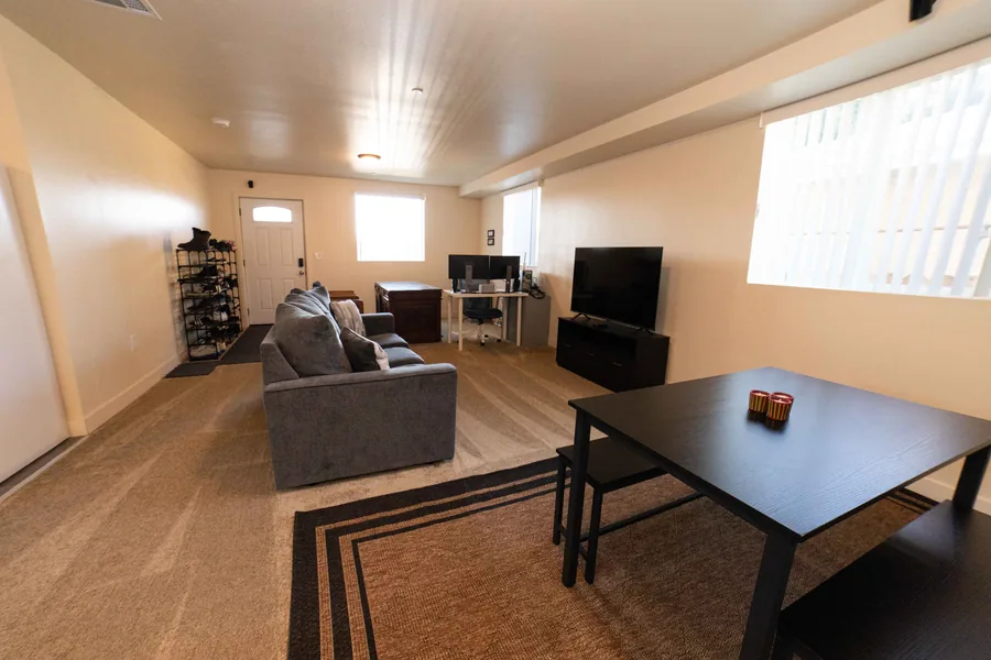 Wide view of the shared common room on East 54th Street with a sofa a dining table and a television