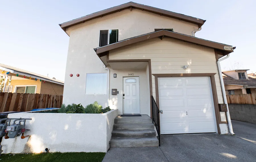 Street view of the Wellness Housing home on East 54th Street in Los Angeles with its front wall and garage