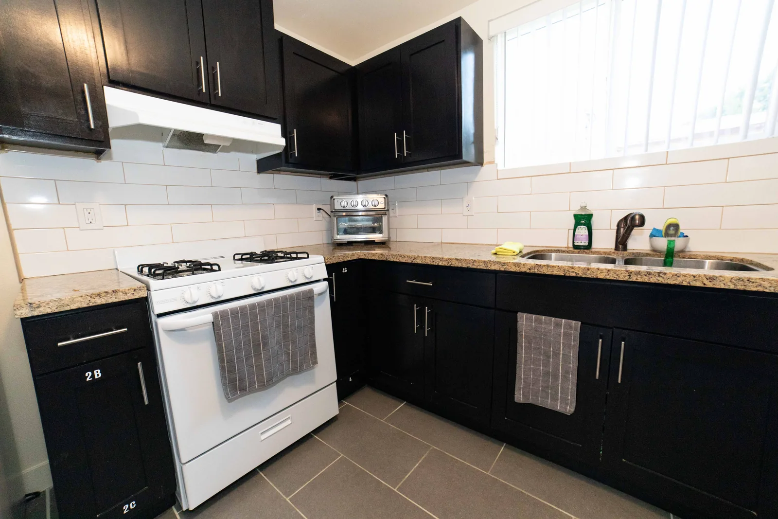 Gas range granite counter and subway tile backsplash in the shared kitchen at the East 54th Street house
