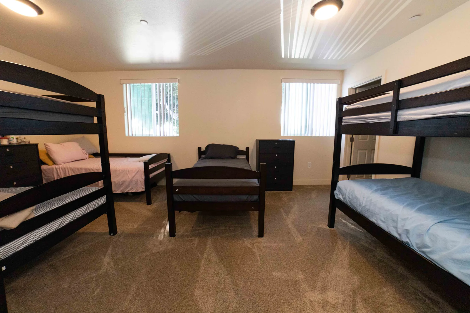Shared bedroom on East 54th Street with two bunk beds two single beds and a chest of drawers for each bed