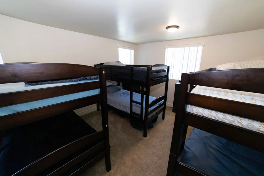 Upstairs shared bedroom on East 54th Street with three bunk beds and windows on two walls