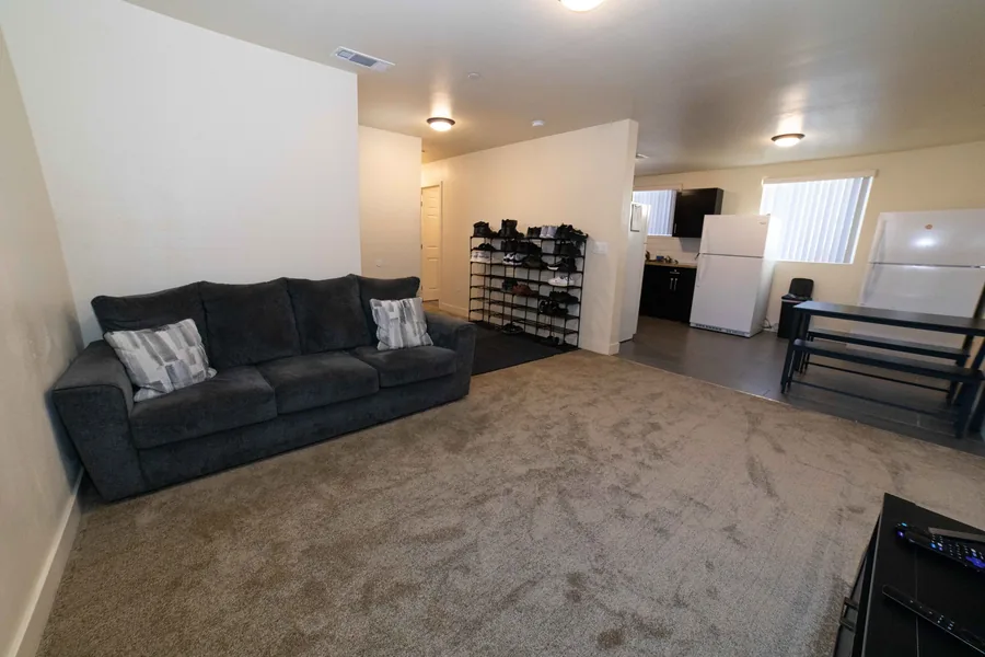 Common room and entry in the East 54th Street upper unit with a sofa a shoe rack and the kitchen beyond