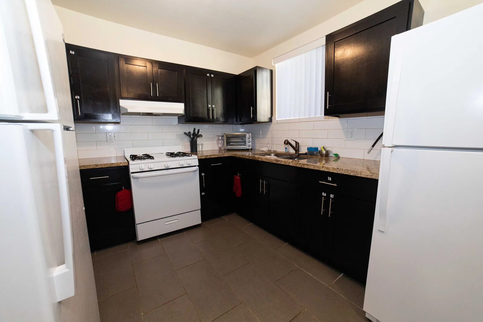Kitchen in the East 54th Street upper unit with dark cabinets a gas range and a full size refrigerator