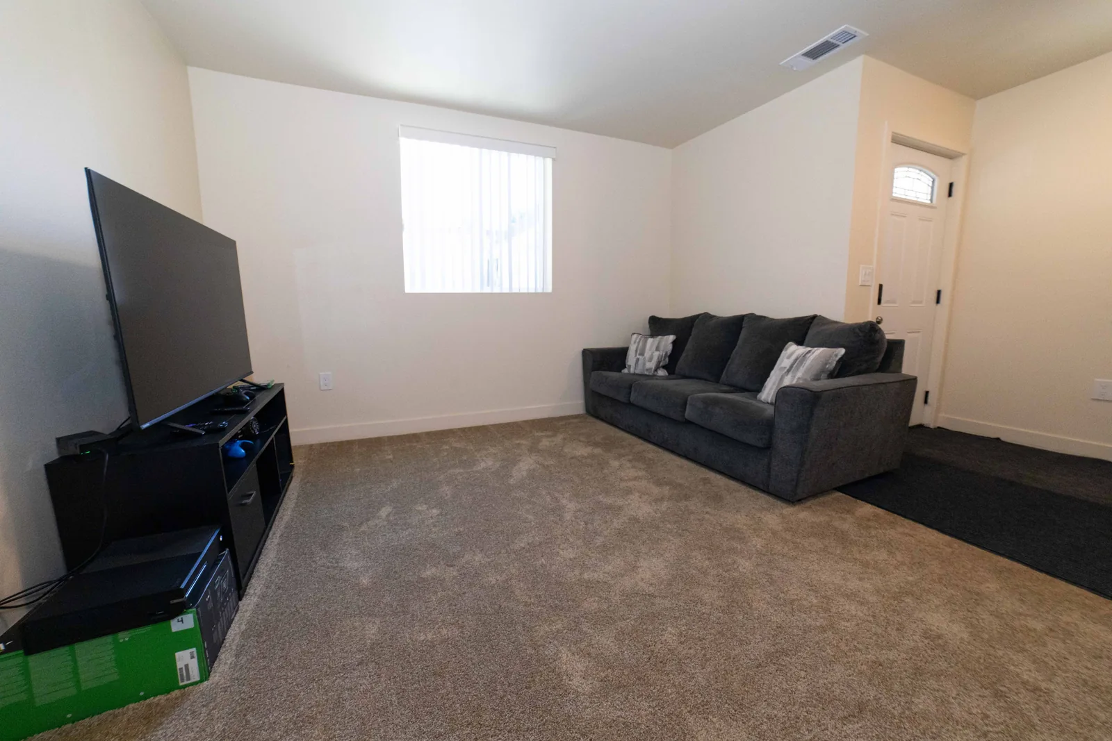Living area in the East 54th Street upper unit with a sofa a large television and the front door