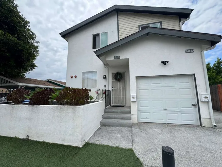 Front of the Wellness Housing home on East 69th Street in Los Angeles with entry steps a garage and a planted front wall