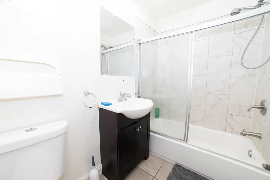 Shared bathroom on West 42nd Street with a tub shower a vanity and a marble effect surround