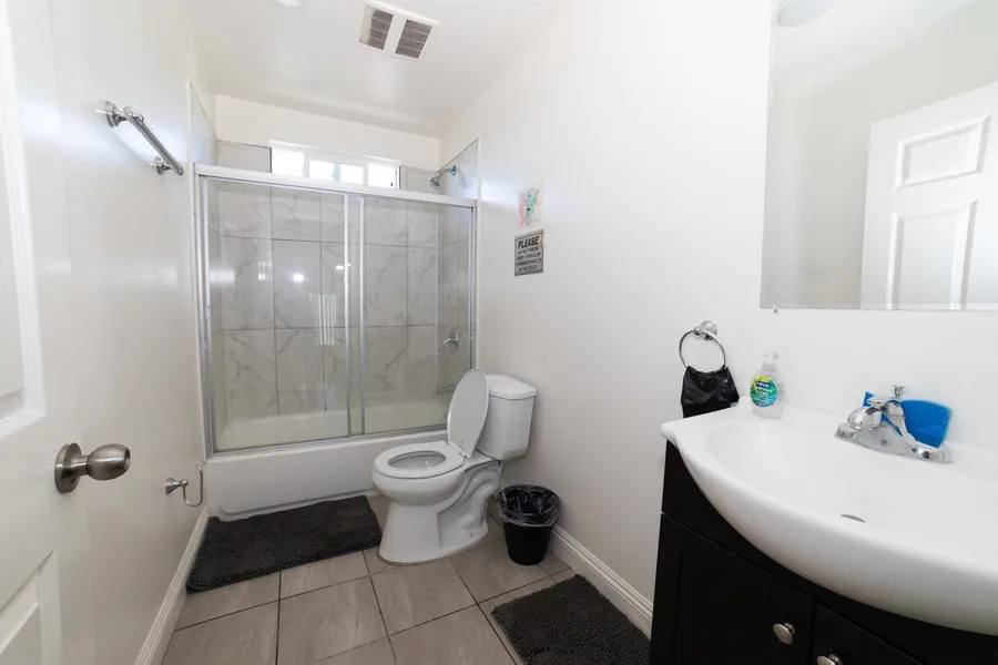 Bathroom at the West 42nd Street house with a tub shower a vanity sink and a tiled floor