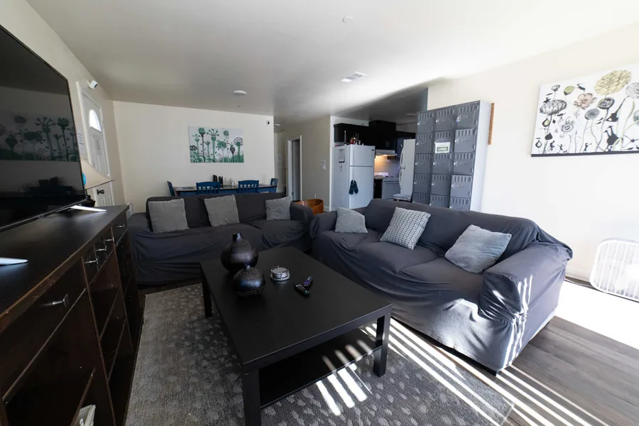 Common room at the West 42nd Street house with sofas a low table and a wall of lockable mail boxes