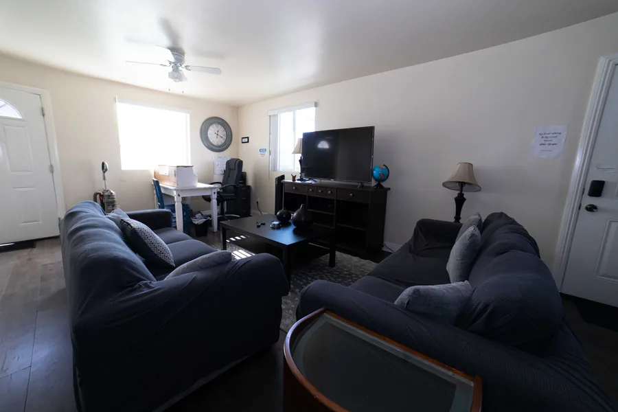 Common room on West 42nd Street with two sofas a television a ceiling fan and a shared desk