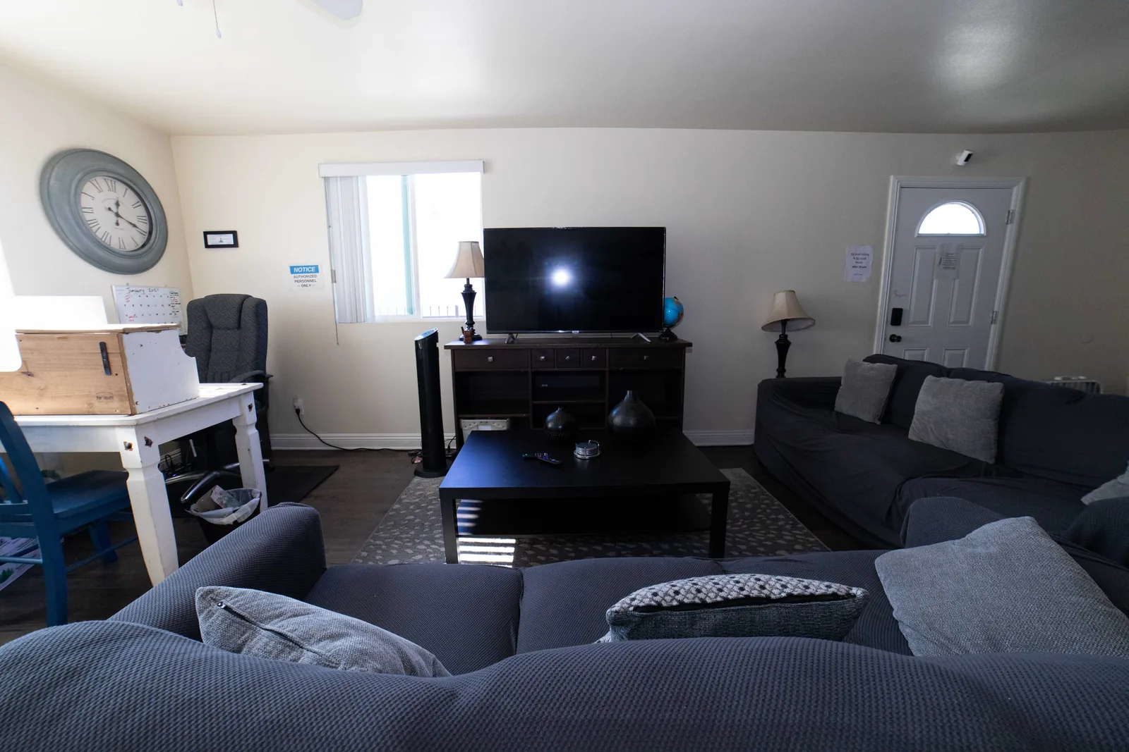 Wide view of the West 42nd Street common room with sofas a coffee table a television and the front door