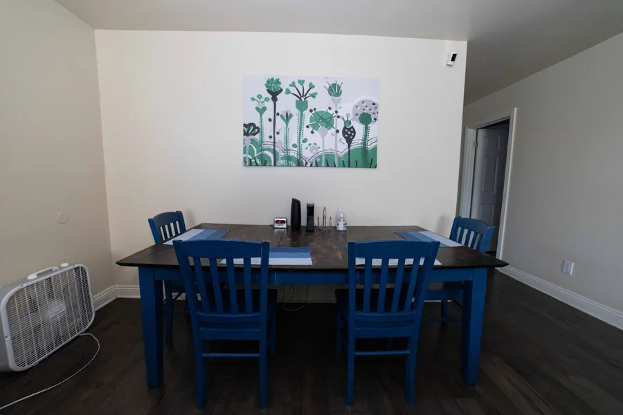 Dining area at the West 42nd Street house with a wooden table and six painted chairs