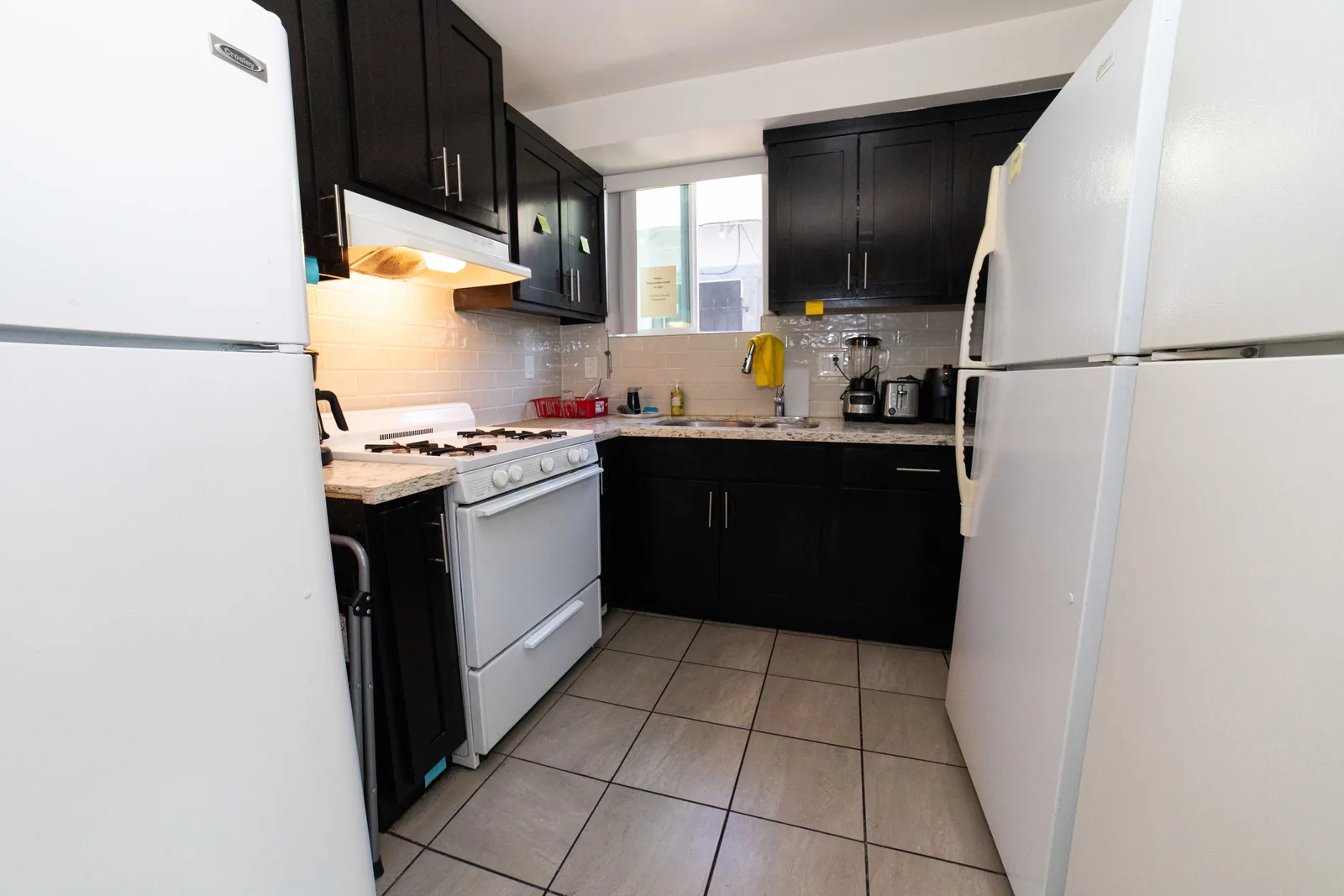 Wide view of the shared kitchen on West 42nd Street with dark cabinets and a full size refrigerator