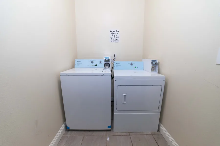 Laundry room at the West 42nd Street house with a washer a dryer and the posted laundry hours above them