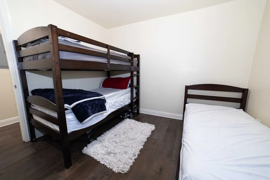Shared bedroom on West 42nd Street with a bunk bed a single bed and a rug between them