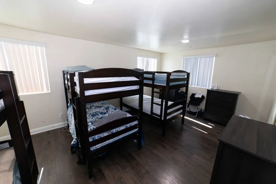 Shared bedroom at the West 42nd Street house with bunk beds a desk and wood look flooring