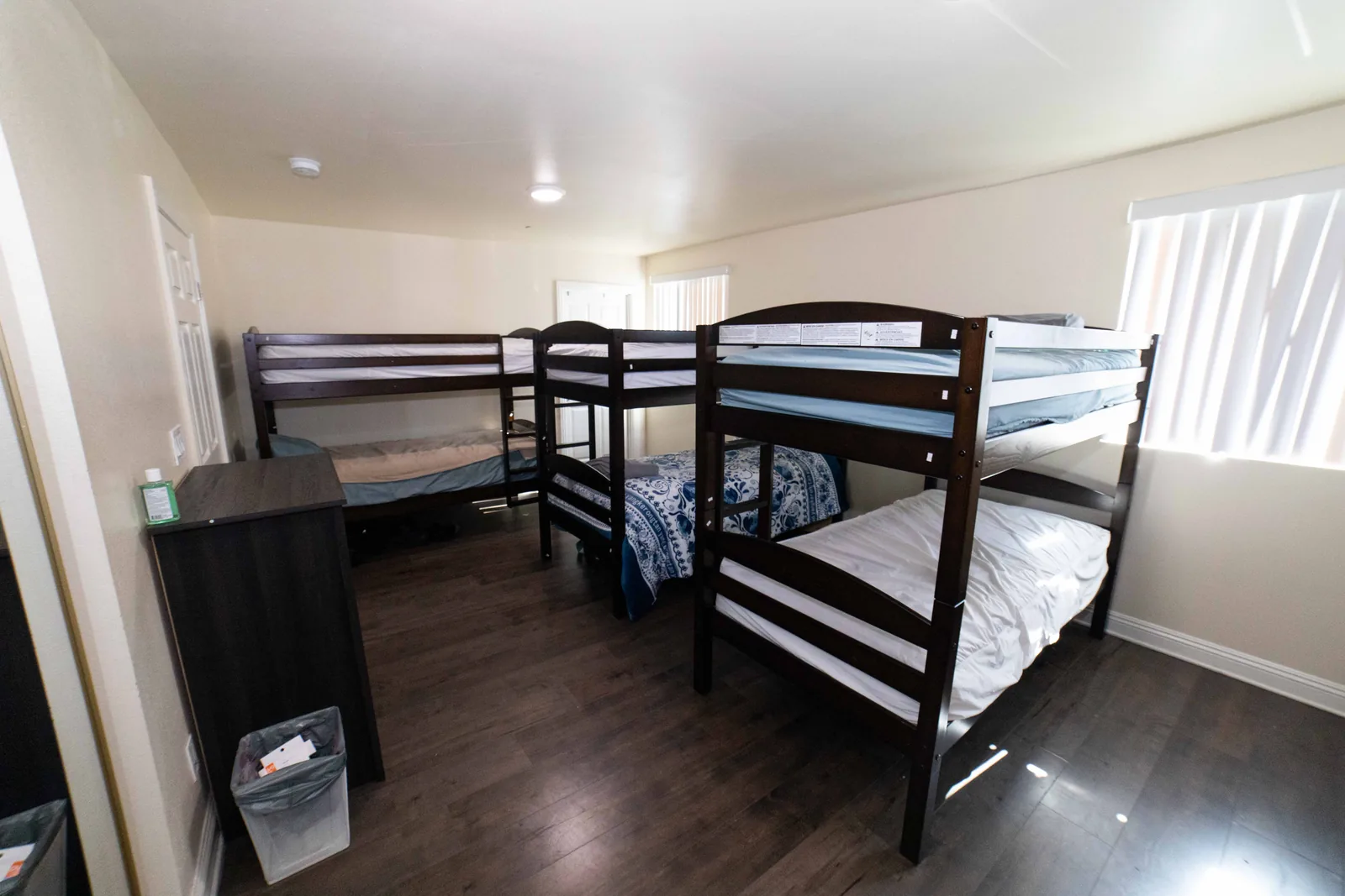 Shared bedroom on West 42nd Street with three bunk beds and a chest of drawers beside each one