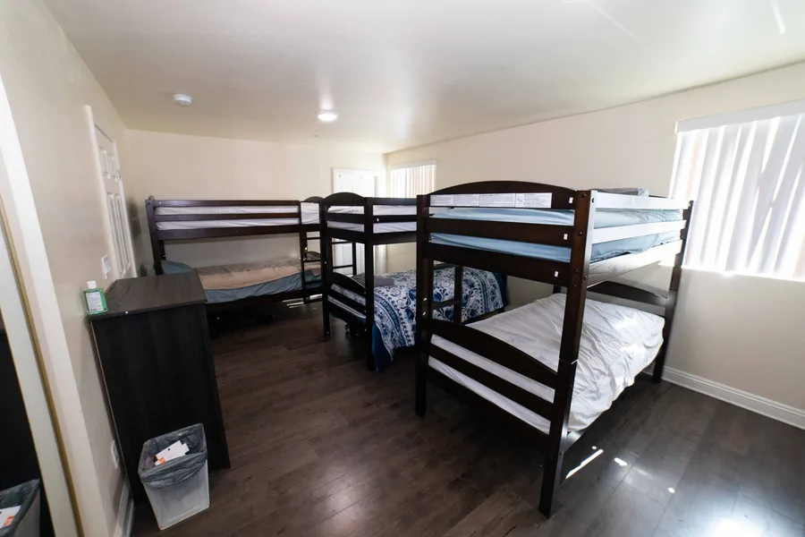 Shared bedroom on West 42nd Street with three bunk beds and a chest of drawers beside each one
