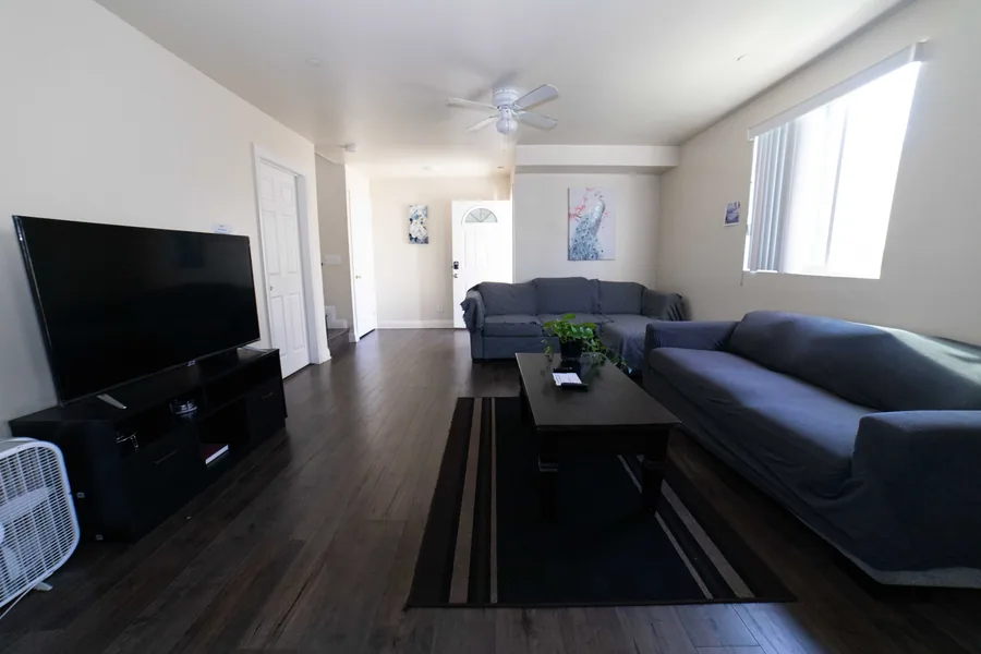 Common room in the West 42nd Street upper unit with sofas a television and a ceiling fan