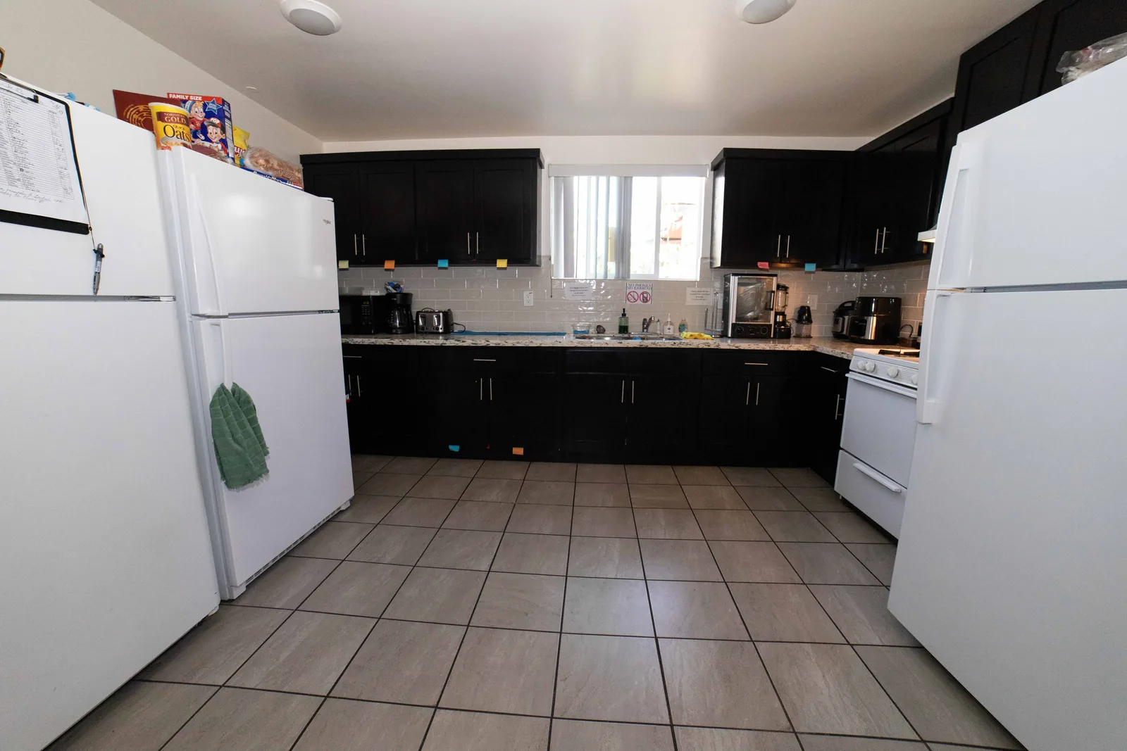 Kitchen in the West 42nd Street upper unit with dark cabinets a gas range and two refrigerators