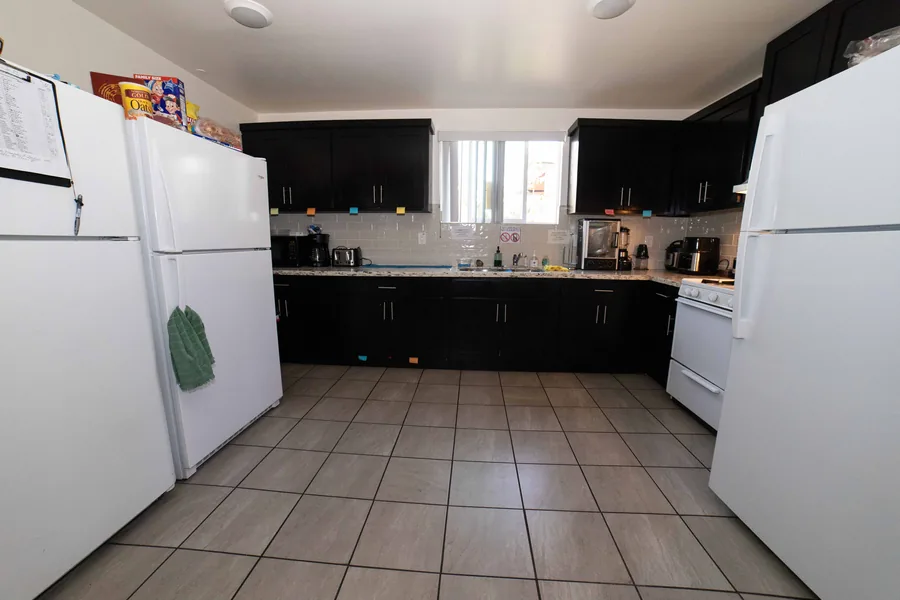 Kitchen in the West 42nd Street upper unit with dark cabinets a gas range and two refrigerators