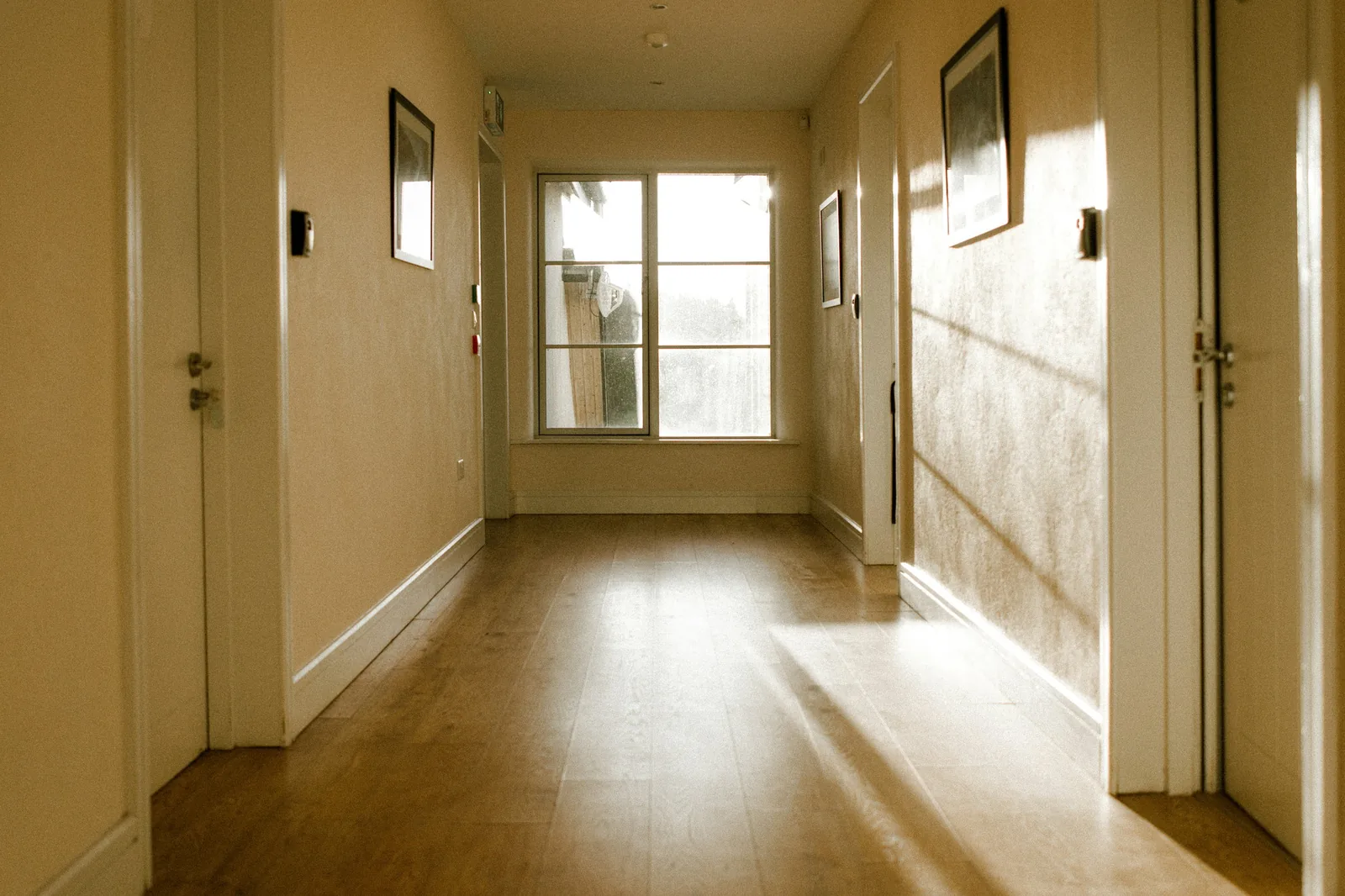 Daylight falling down a residential hallway with closed doors along both sides
