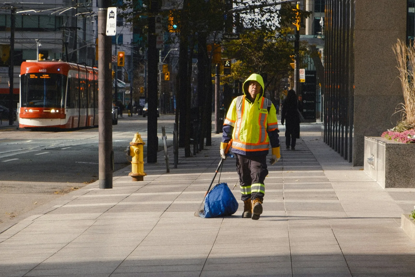 A person walking along a city pavement pulling a bag behind them